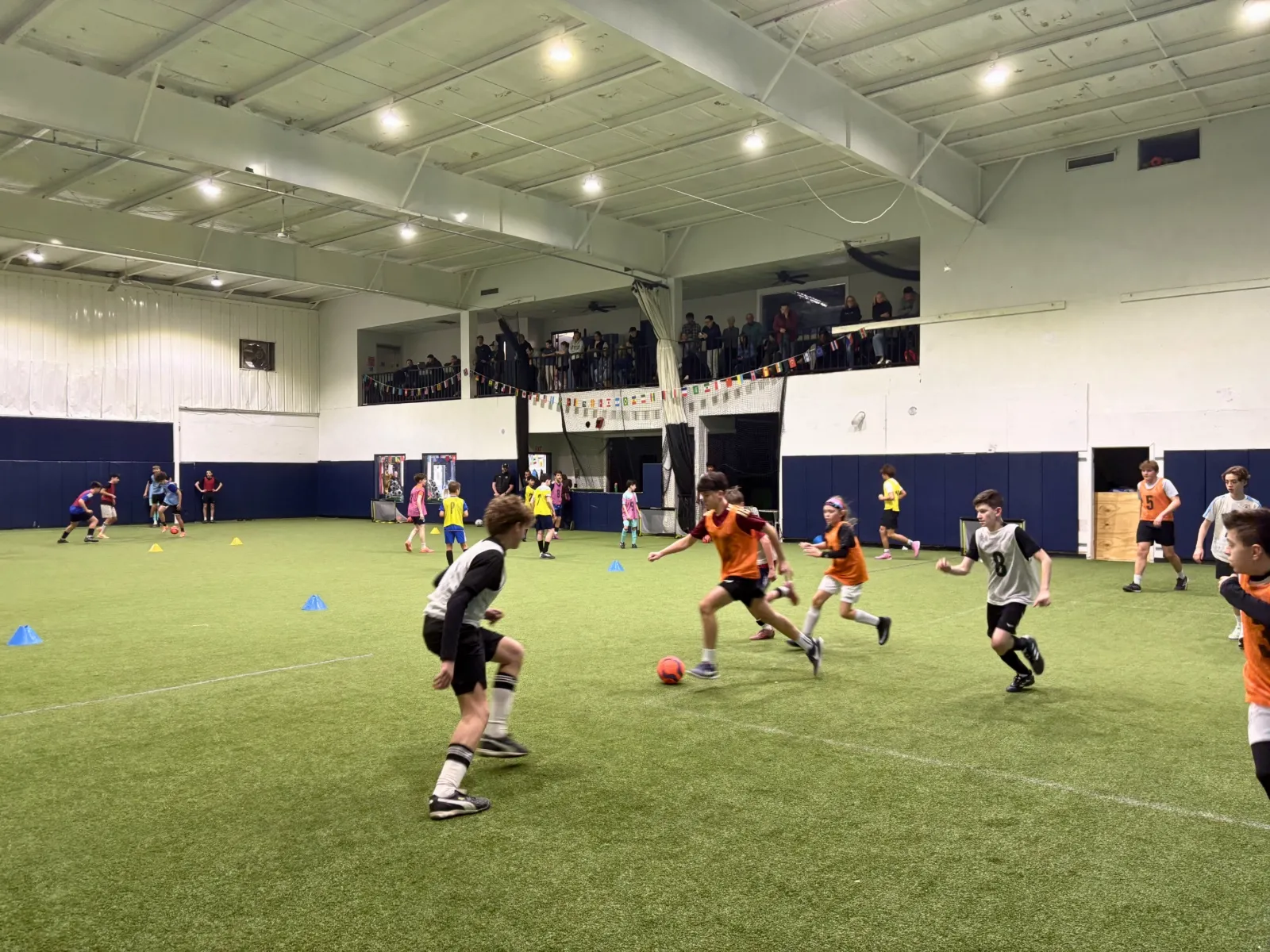 Campers playing a fast-paced soccer game on the indoor turf at Bedford Field House.