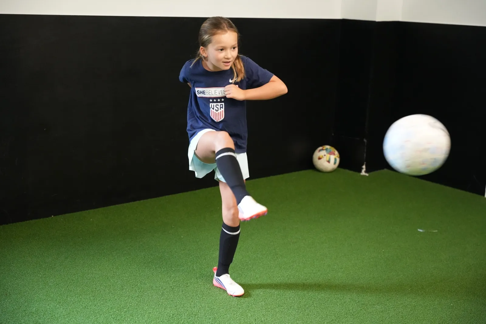 Young athlete practicing a soccer kick on the indoor turf at Bedford Field House.